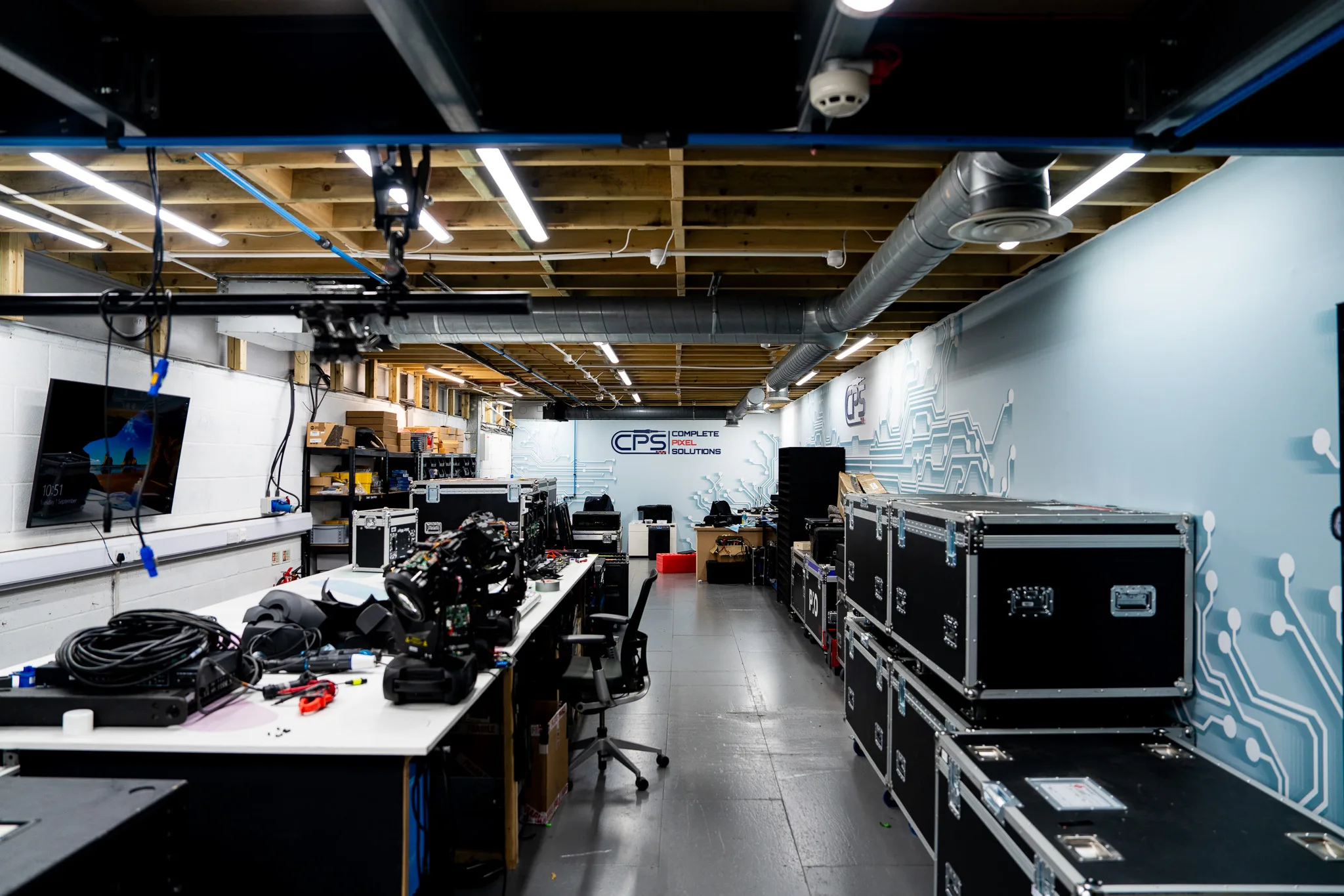 CPS workshop interior with repair benches on one side and stacked flight cases on the other