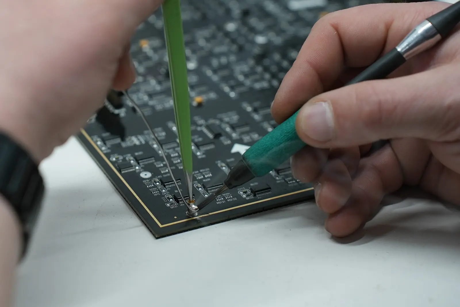 Technician soldering a component on a circuit board using a fine tip iron