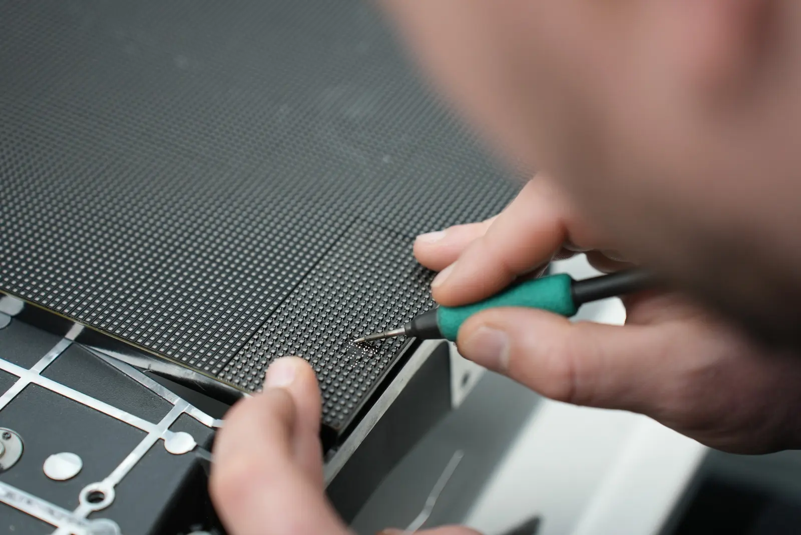 Technician using a precision tool to repair an individual pixel on an LED display module